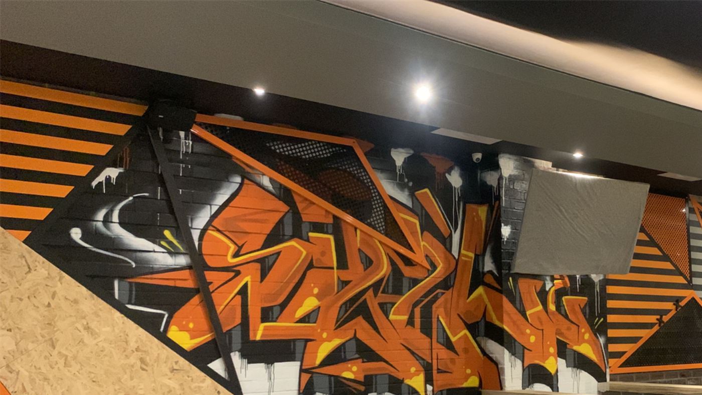 Orange and black graffiti lettering across a restaurant interior wall